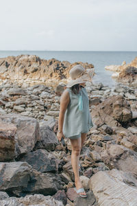 Beautiful woman walking on rock over sea