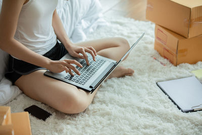 Low section of woman using laptop while sitting at home