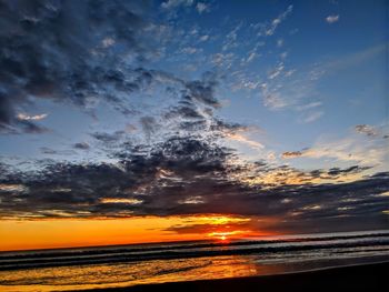 Scenic view of sea against dramatic sky during sunset