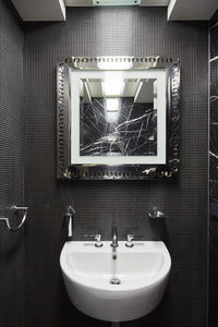 Sink and cracked mirror in bathroom