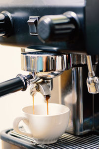 Close-up of coffee maker pouring drink in cup