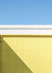 Yellow warehouse with shadow and blue sky