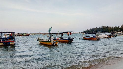 Boats moored in sea against sky in city