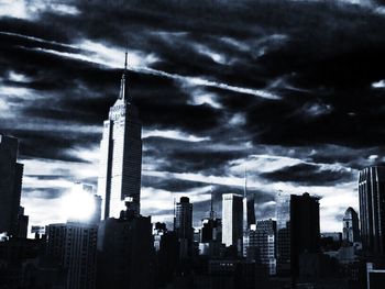 Low angle view of skyscrapers against cloudy sky