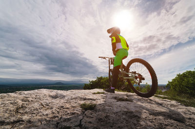 Young man in sportswear stands near a mountain bike and looks to the side while choosing a