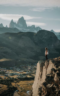 Woman standing on rock against sky