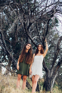 Happy young woman standing by tree in forest