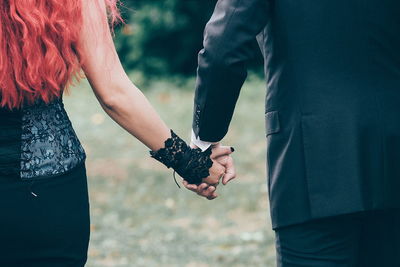 Midsection of wedding couple holding hands
