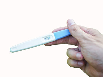 Close-up of hand holding camera against white background