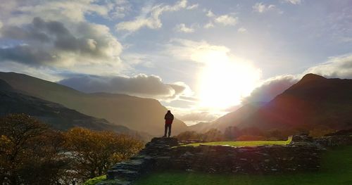 Man standing on mountain against sky during sunset