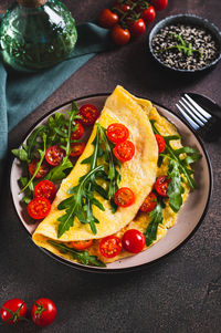 Omelette pancake with cherry tomatoes and arugula on a plate on the table vertical view