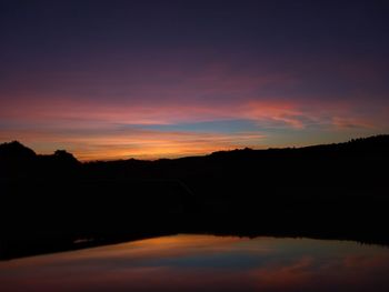 Scenic view of silhouette landscape against dramatic sky during sunset