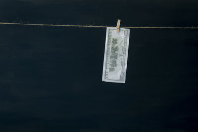 Close-up of clothespins hanging on rope against black background