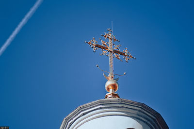 Low angle view of cross by building against clear blue sky