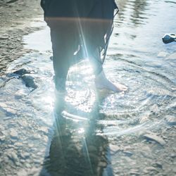 Low section of person standing in swimming pool