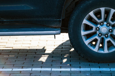 Suv fragment with rear wheel, car shadow on the pavement on a sunny day, closeup
