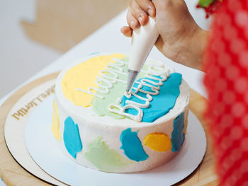 Midsection of person holding cake on table