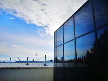 Low angle view of buildings against sky seen through glass window