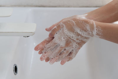 Cropped hands of woman cleaning hands in bathroom