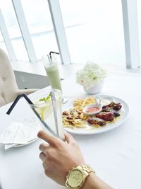 Cropped hand of man holding drinking glass in restaurant