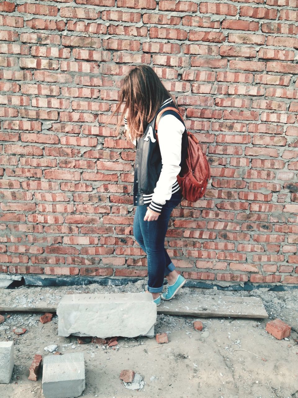 full length, brick wall, lifestyles, casual clothing, young adult, leisure activity, standing, young women, wall - building feature, built structure, architecture, building exterior, person, long hair, stone wall, front view, side view, red