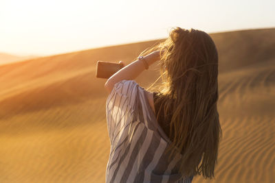 Rear view of woman photographing at dessert