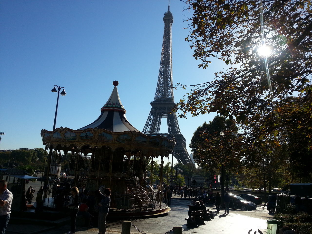 clear sky, built structure, tree, architecture, building exterior, sunlight, low angle view, eiffel tower, travel destinations, incidental people, sky, famous place, travel, street light, outdoors, city, tower, day, tourism, sun