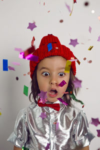 Portrait surprise in knitted hat boy child in silver shirt and red bow tie catches glitter confetti