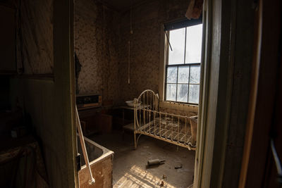 Interior of abandoned house in ghost town with baby cradle