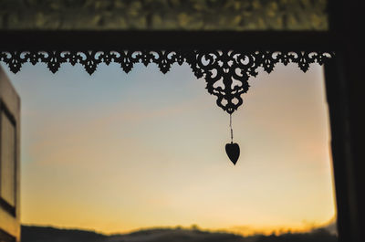 Low angle view of silhouette decorations hanging against sky at sunset