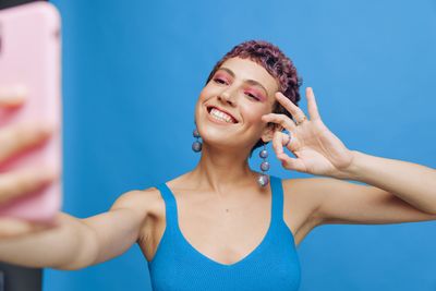 Portrait of smiling young woman looking away against blue background