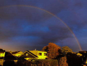 Low angle view of rainbow over buildings against sky