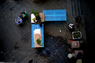 High angle view of people sitting on chair by blue tables at walkway