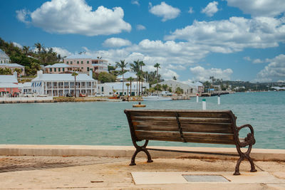 Chairs on beach by swimming pool against sky