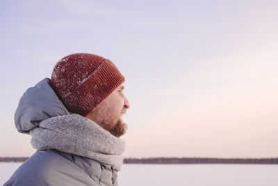 Mid adult man wearing warm clothing looking against sky during sunset