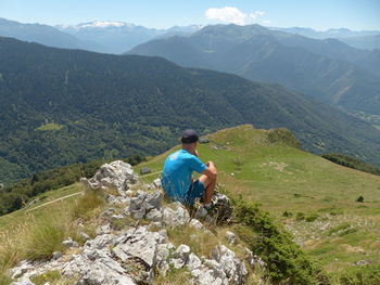 Rear view of man sitting on mountain