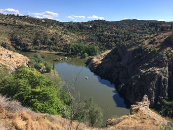 Scenic view of river by mountains against sky