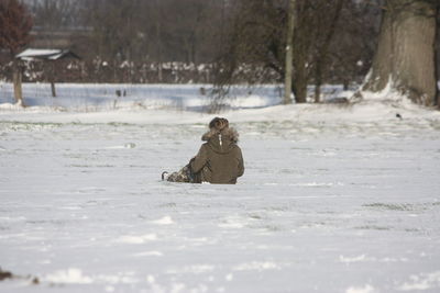 Person sitting on snow covered land