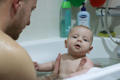 Cheerful father and son taking bath at bathroom