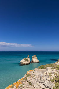 Rocks in sea against blue sky