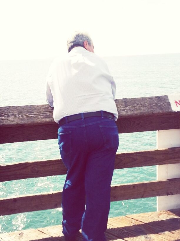 sea, rear view, water, standing, lifestyles, casual clothing, leisure activity, beach, railing, horizon over water, day, shore, full length, outdoors, men, three quarter length, sunlight, clear sky