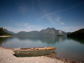 Abandoned fishing boat on bank of alps lake. morning lake glowing by sunlight.