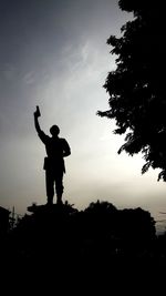 Silhouette man standing on field against sky during sunset