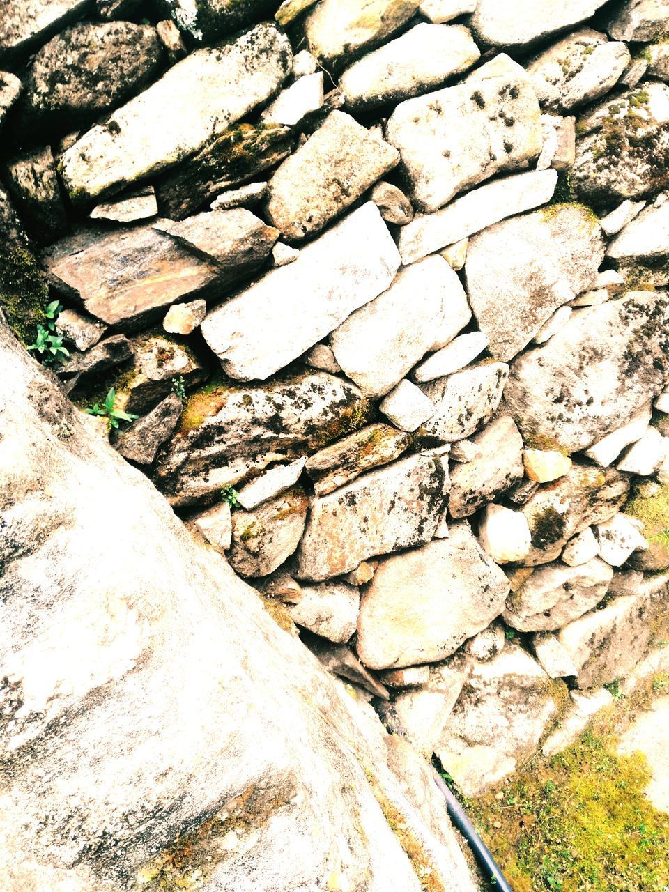 HIGH ANGLE VIEW OF STONE WALL BY ROCKS