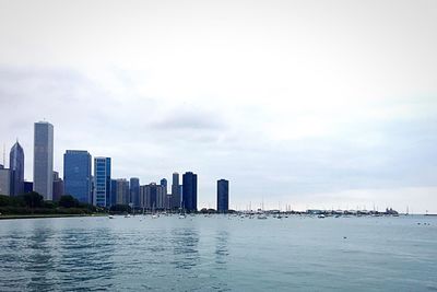 City at waterfront against cloudy sky