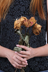 Midsection of women holding wilted flowers