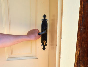 Woman holding a handle while opening a wooden door