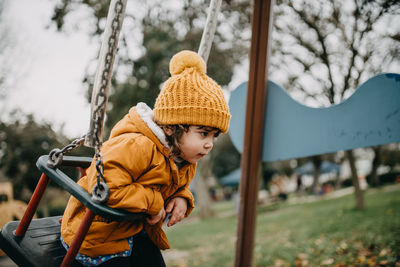 Girl sitting on swing in playground