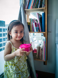 Toddler girl playing toy kitchen at home.