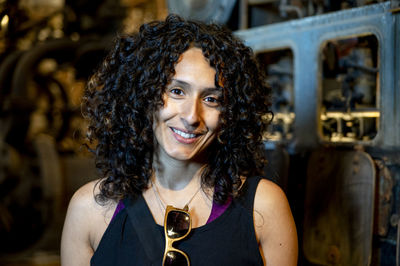 Portrait of a mixed race woman smiling while posing inside an abandoned factory.